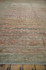 A low-angle view highlighting the heavy abrashes and worn texture of a distressed antique Fereghan carpet.