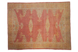 Vintage distressed Oushak carpet in faded cochineal red with a splayed gold and ivory medallion.