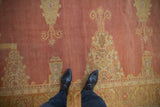 Close-up of the distressed texture and speckled abrash on a faded red vintage Oushak carpet.