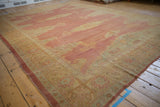 Angled perspective of a distressed Turkish Oushak showing the faded red field and gold and seafoam border.