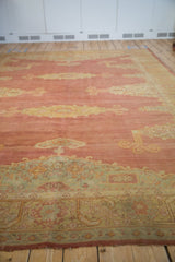 Low-angle view of a vintage Oushak highlighting its faded red pile and seafoam green border.