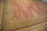 Angled view of a vintage Oushak carpet showing its full length and faded red and gold motifs.