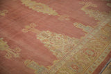 A fine-woven vintage Oushak carpet showing speckled abrash across its faded dusty cochineal red field.