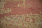 The distressed, low-pile texture and visible knot heads of a vintage Turkish Oushak carpet.