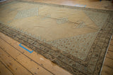 Low-angle perspective on the distressed texture and geometric serpent border of a Malayer carpet.