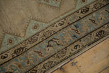 A detailed view of the evenly worn pile showing exposed knot heads on the geometric border.