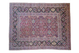 Antique Meshed carpet with a magenta arabesque field and a wide, dark navy floral border.