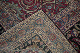 The wide, ivory and blue floral border shown on a folded corner of an antique magenta Meshed carpet.