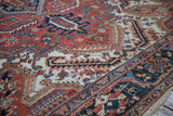 Angled view of the textured pile and unusual arabesque border on a vintage Heriz carpet.