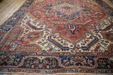 Angled view of a vintage Heriz carpet highlighting the geometric border and central stepped medallion.