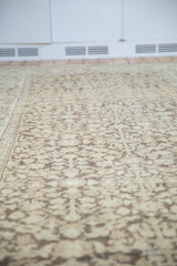 Distressed vintage Mahal carpet detail showing faded coffee brown shrub and henna plant motifs over worn beige pile.