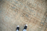 Softly worn texture on a distressed antique Kerman carpet showing its faded central medallion and florals.