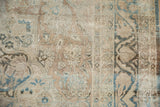 Detailed view of the distressed wool pile, revealing knot heads and floral motifs on an antique Kerman rug.