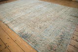 Angled view of the antique Kerman carpet, showing the flowing floral design and soft, time-worn texture.