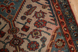 Detail of a vintage Hamadan rug, with softened red, dusty blue, and beige patterns.