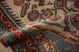 Close-up vintage Hamadan rug: madder root red boteh border, dusty blue motifs, and beige field.