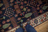 Baktiari rug runner featuring navy field with tree of life motifs and beige floral border.