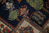 Close-up of vintage Baktiari rug, navy field, celadon green tree-of-life, and patterned beige border.