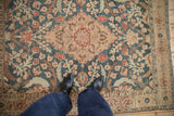 Looking down at the low, distressed pile of a vintage Tabriz rug in dusty teal and sand.