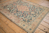 Overhead angled view of a distressed Tabriz rug with a sand medallion and dusty teal floral field.