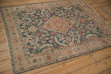 Angled view of a vintage distressed Tabriz rug with faded teal, sand, and terracotta florals.