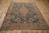 Angled view of a vintage Tabriz rug showing its distressed texture and teal and terracotta pattern.