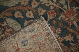 Corner of a distressed Tabriz rug folded back to reveal the hand-knotted weave and teal pile.