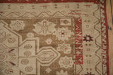 Distressed antique Caucasian rug corner, coffee brown geometric field with stylized leaves, brick red border.