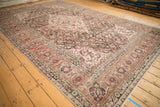 Angled view of a vintage Tabriz carpet displaying its oversized Herati design and raspberry accents.