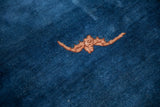 A copper-toned bat motif on the low cobalt blue pile of an antique Peking rug.