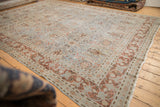Distressed vintage Tabriz carpet corner showcasing pale blue floral trellis, copper arabesques, and tattered edge.
