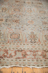 Distressed vintage Tabriz carpet section with scrolling floral vinery, worn dusty blue pile, and tattered fringe.