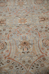 Distressed vintage Tabriz carpet showing faded slate blue field and pale copper trellis-stylized vinery.