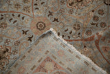 Distressed vintage Tabriz rug close-up, showing worn dusty blue floral pile and hand-knotted foundation.