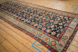 Antique Northwest Persian runner's ivory and madder root red borders framing a navy floral field.