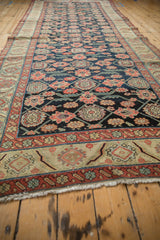 Antique Persian runner's secured end with beige fringe and patterned red-orange border.