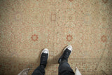 Distressed antique Tabriz carpet with intricate terracotta vine medallions and worn ivory pile.
