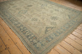 Angled view of a vintage distressed Oushak carpet's soft, low-pile texture and muted green palette.