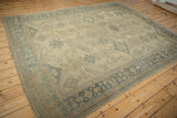 Angled view of a distressed Oushak carpet showing its low, even pile and time-softened colors.