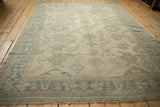 Angled perspective of a vintage Oushak showing the geometric border and evenly worn pile of the field.
