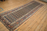 Intricate floral cross sections on aubergine border of antique Kurdish runner with navy boteh field.