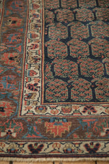 Antique Kurdish runner displaying deep navy field with staggered red boteh motifs and detailed ivory floral main border.