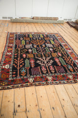 Vintage Bakhtiari rug corner with dark navy garden design, colorful trees, and red vine border.