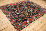 Vintage Bakhtiari rug corner with red meandering vine border and dark navy garden design.