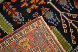 Folded corner of vintage Bakhtiari rug showing intricate border motifs, original side cord, and hand-knotted back.