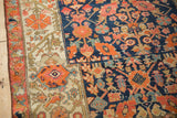 An antique Malayer rug's oversized Herati border in beige next to its dense navy and orange field.
