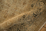 Angled view of a distressed Tabriz rug showing the low-pile texture and turtle samovar border detail.