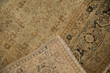 Folded corner of an antique Tabriz rug showing the hand-knotted weave and cotton foundation.