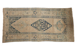 Antique distressed Kurdish runner with a geometric navy blue diamond medallion on a neutral sand and ivory field.