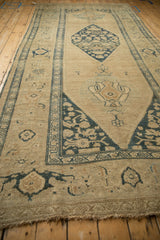 Angled perspective of a long antique Kurdish runner with a central diamond-shaped medallion.